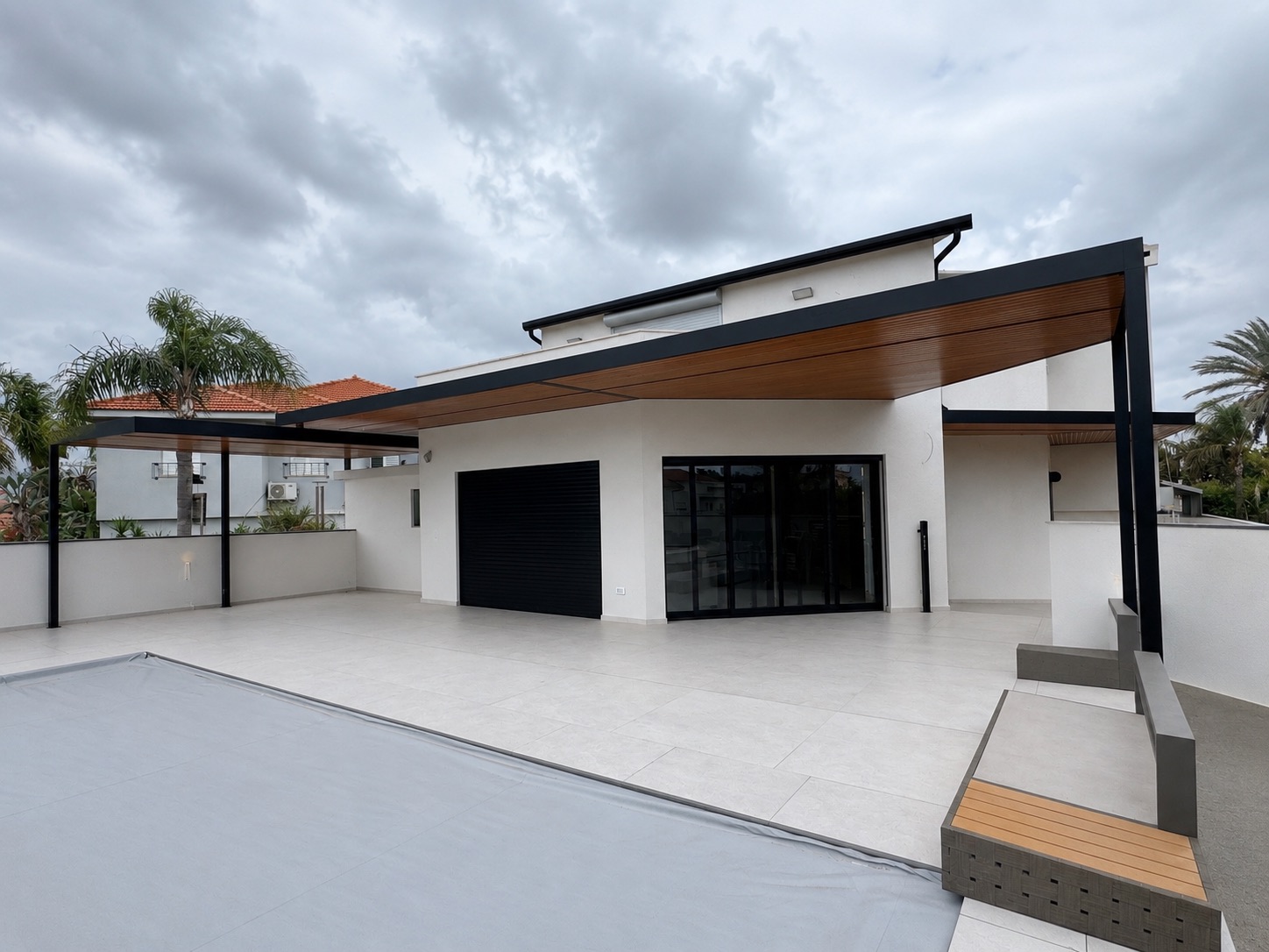 פרגולת אלומיניום עם soffit עץ ומרפסת גג רחבה בבית לבן מודרני